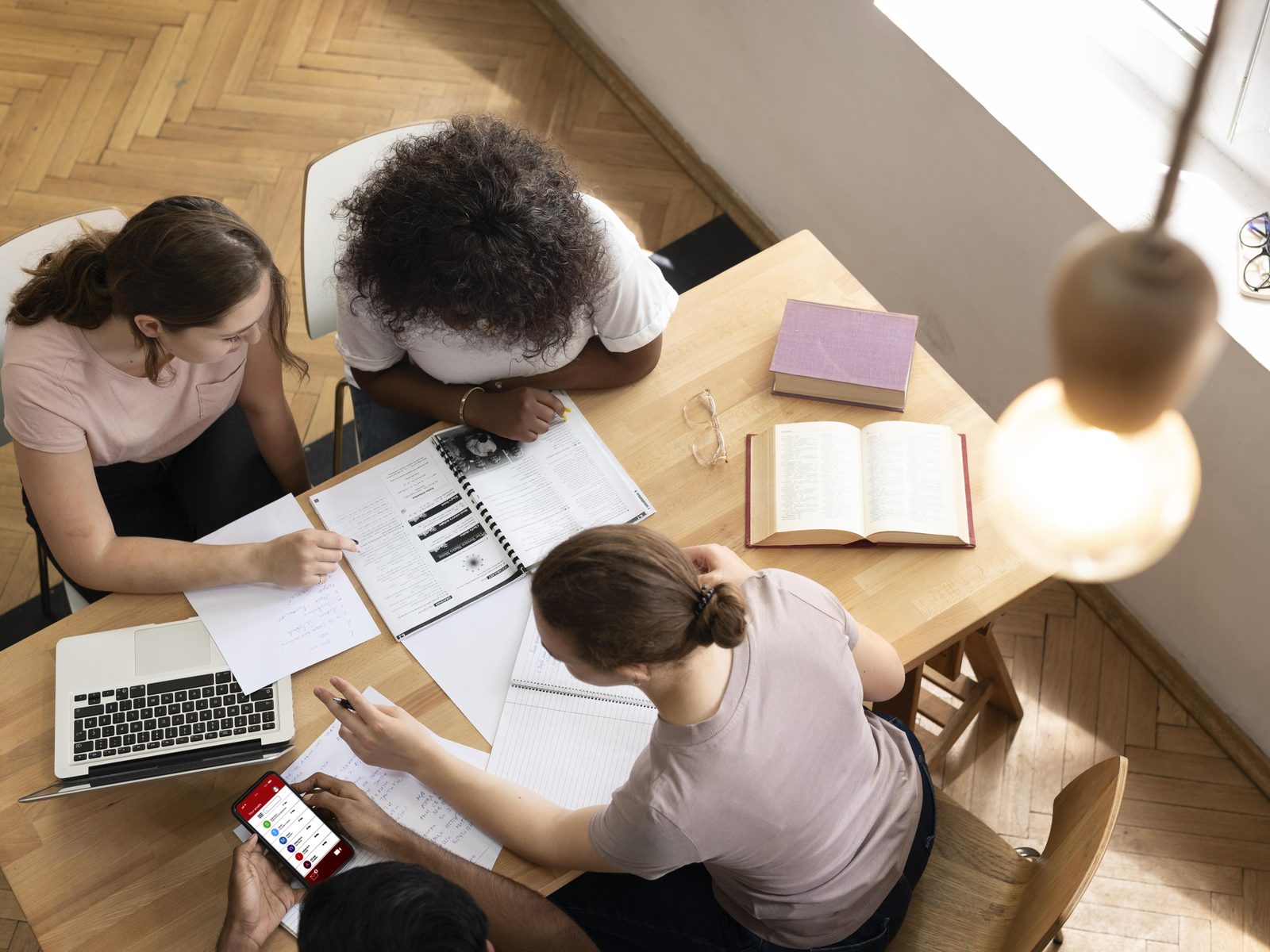 Three students with a laptop and open textbooks studying for a bachelor's degree in general studies