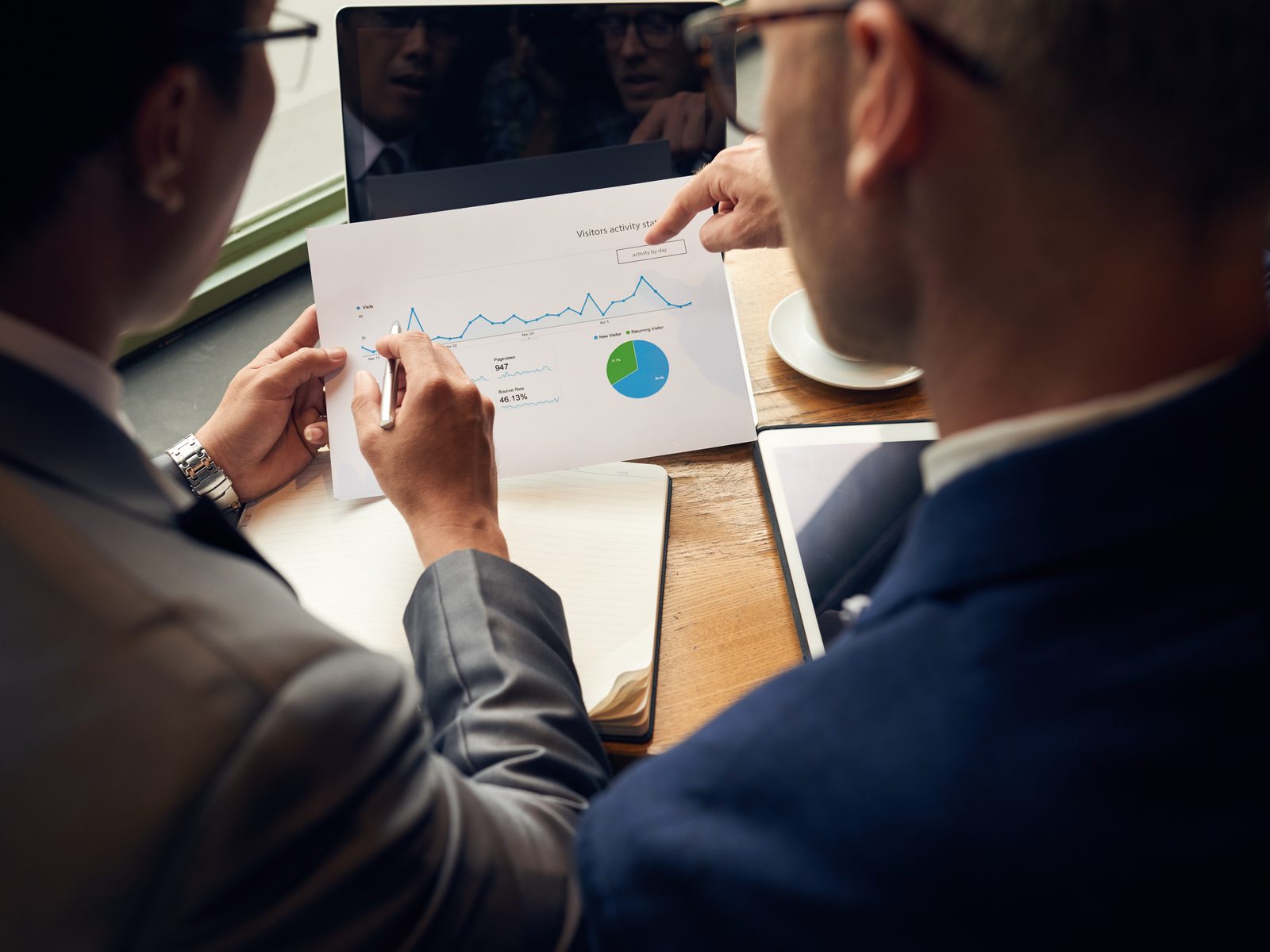 Market research analysts going over a printed sales trend chart and pie chart at a table